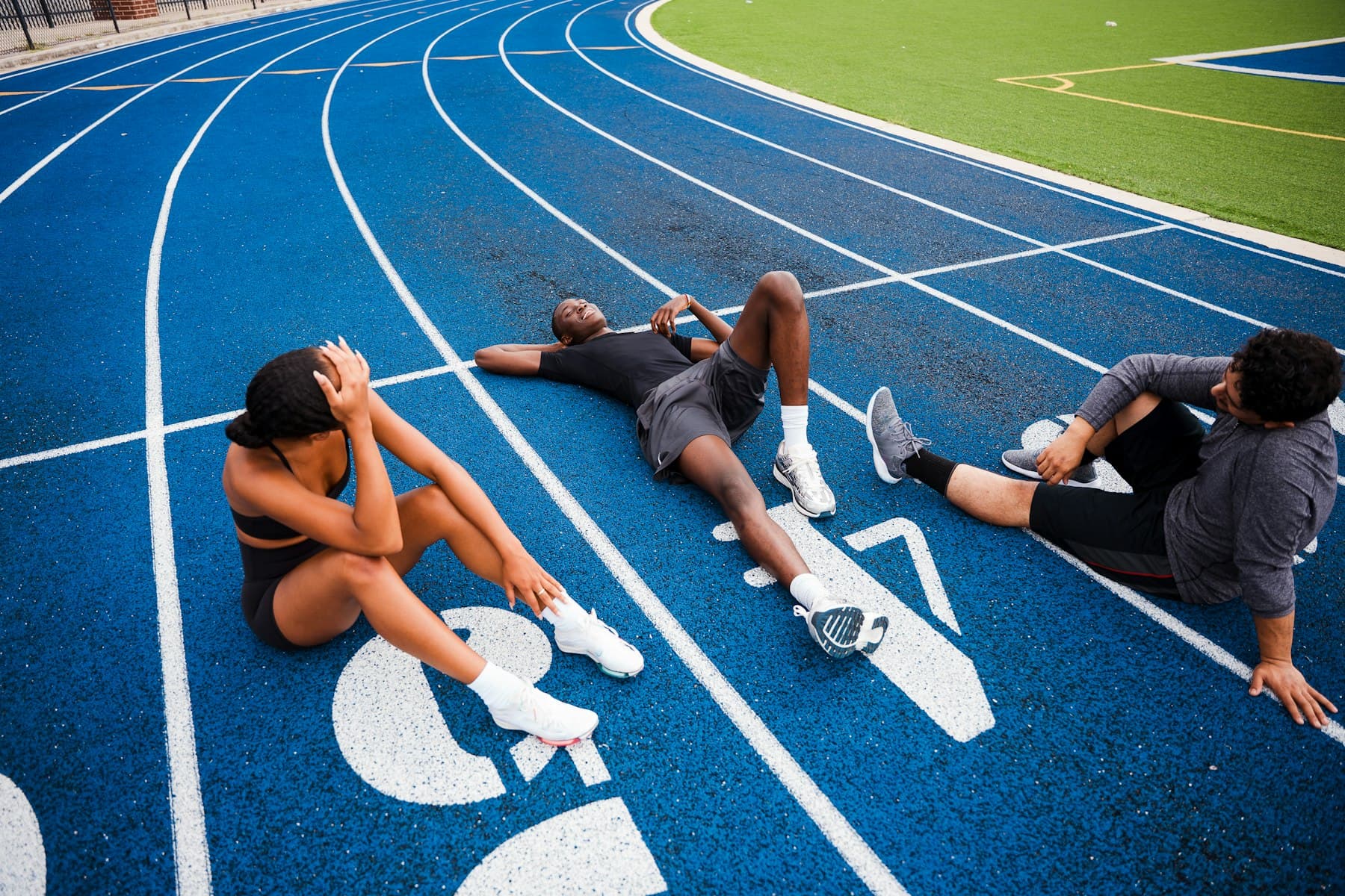 Runners sitting and lying on a blue running track after a session